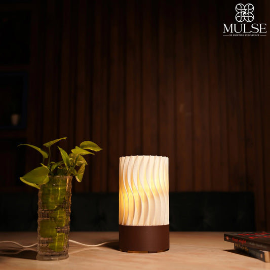 Modern 3D printed table lamp with wavy pattern, next to a green plant in a glass vase