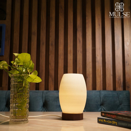 Modern table lamp with textured shade, glass vase with green plant, books on wooden table