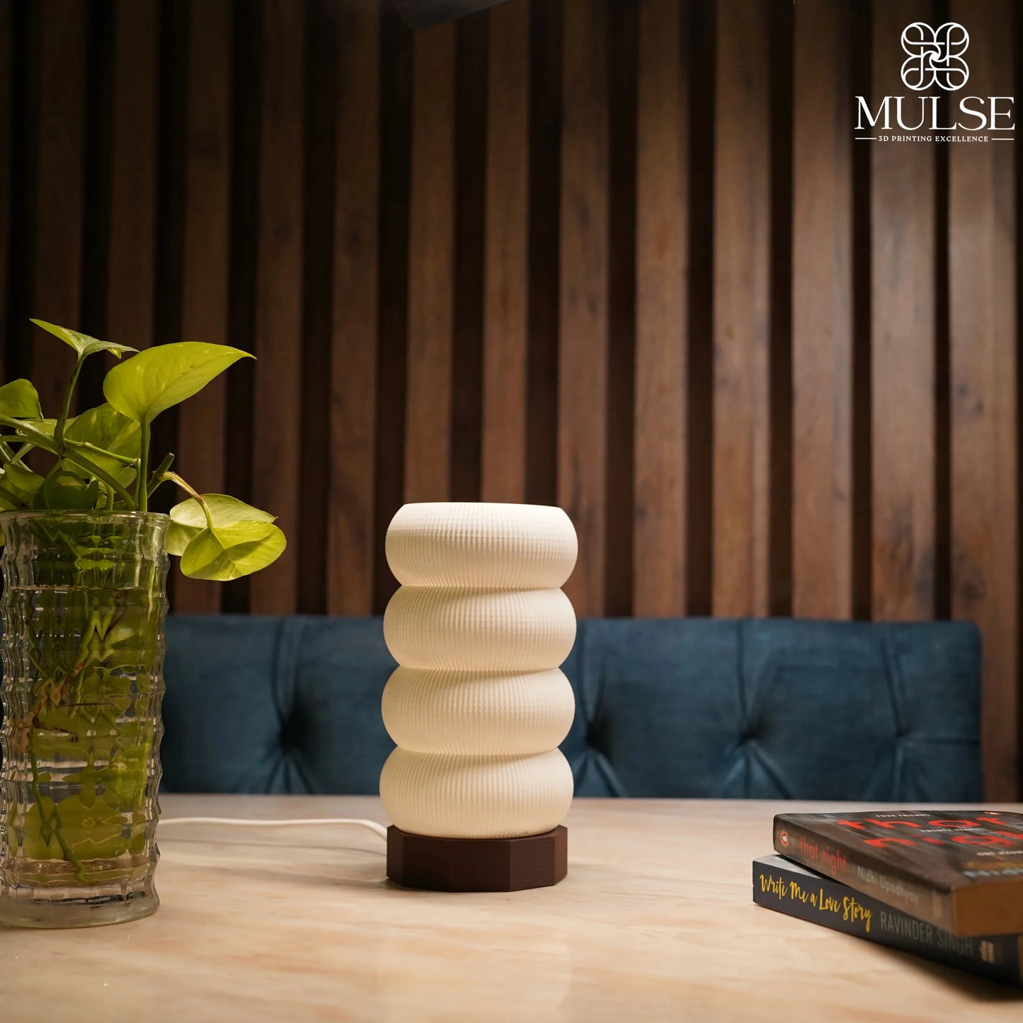 Modern textured table lamp on a wooden desk with a glass plant and books, cozy interior decor